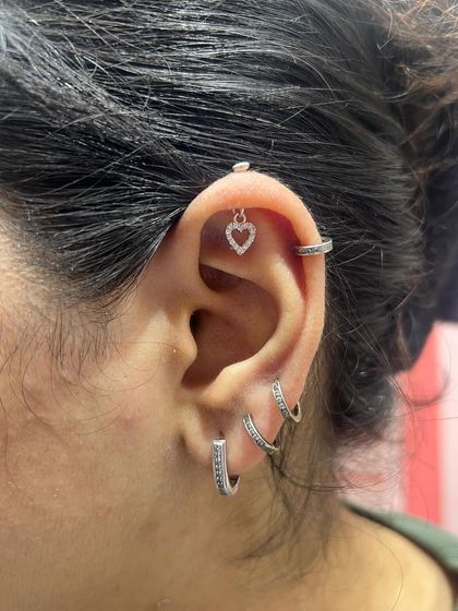 A simple and classic stack with a small heart hanging, a helix ring, and two sparkling hoops.