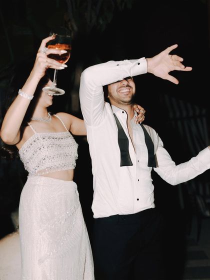 Unrestrained joy on the dance floor. This photo captures the energy of the cocktail party, with the couple laughing and celebrating with a drink in hand.
