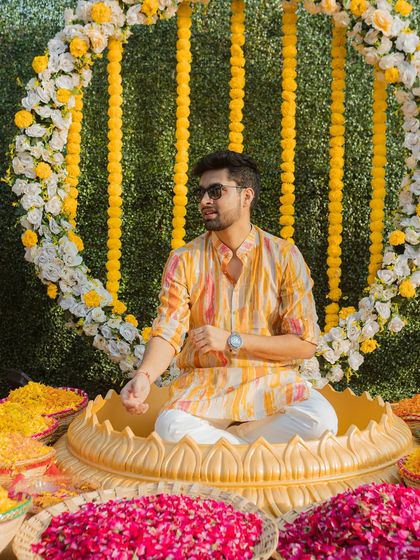 The groom seated in a lotus-shaped vessel, ready for the Haldi rituals to begin. We capture the beautiful decor and setup of your events.