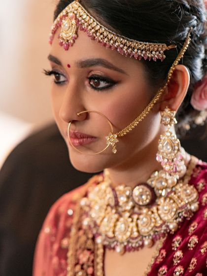 A close-up showcasing the rich tones and striking details of this bridal look. The defined eyes, paired with a traditional nath and mathapatti, create a vision of classic beauty.