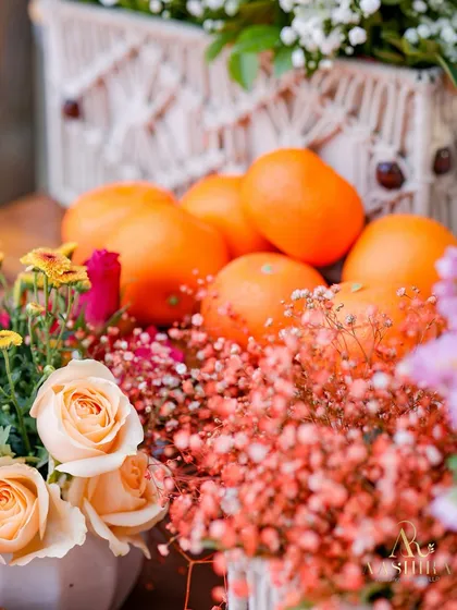 A close-up of the decor, showing a beautiful mix of peach roses, orange baby's breath, and fresh oranges next to a macrame-detailed box.