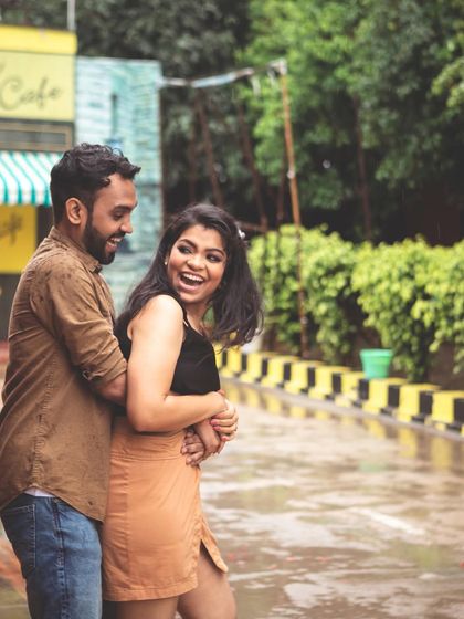 A fun and candid moment of the couple laughing and playing in a colorful, street-like setting, perfect for a casual pre-wedding shoot.