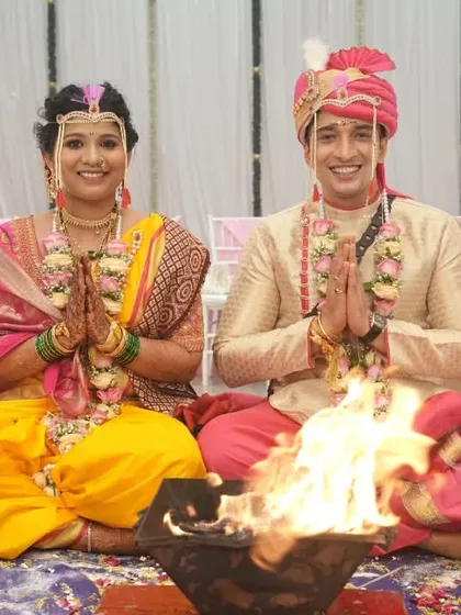 A couple seated before the sacred fire (homa) during their wedding ceremony, joining their hands in prayer.