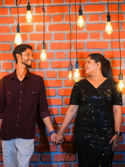 A beautiful shot of a couple holding hands, surrounded by hanging Edison bulbs against a brick wall. This setup has a trendy, industrial-chic vibe.