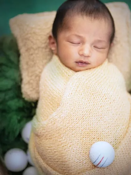 Wrapped in a soft yellow swaddle, this newborn is perfectly coordinated with the golf theme.