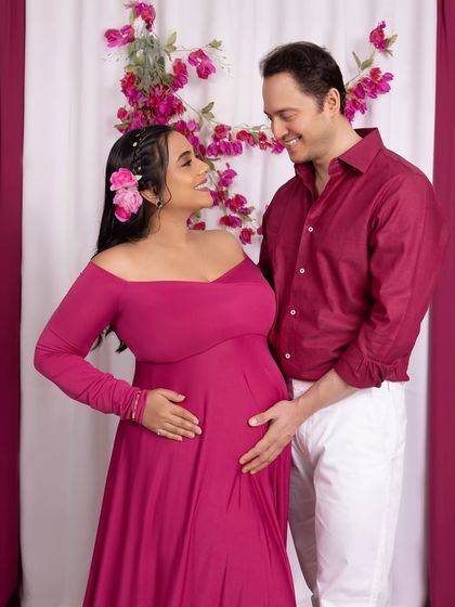 A candid shot of the couple sharing a look of love and laughter during their floral-themed maternity session.
