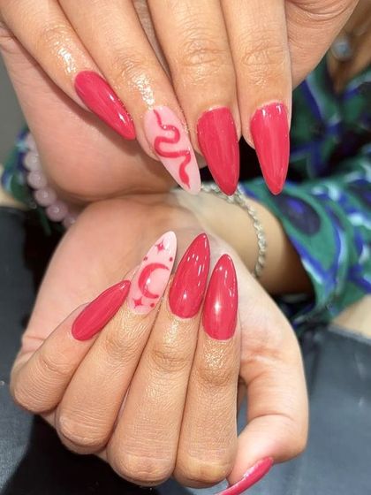 A cool and edgy pink set with accent nails featuring a snake, crescent moon, and stars.