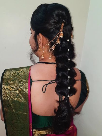 A side view of a bubble braid, a modern take on the traditional braid. It's decorated with pearls and a stylish side hair chain (maang tikka extension) for a contemporary touch.
