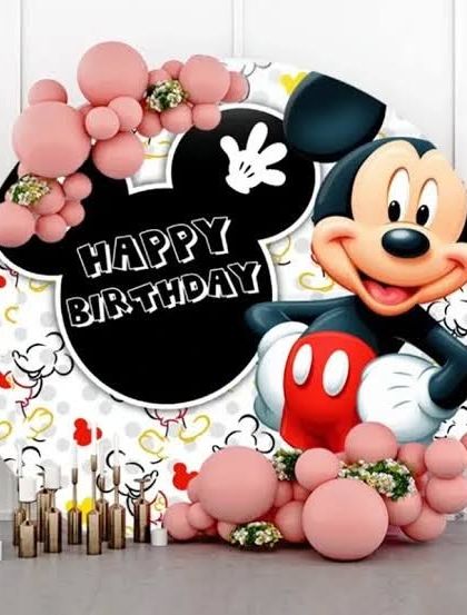 A classic Mickey Mouse themed birthday backdrop, featuring a large character print and pink balloon accents.