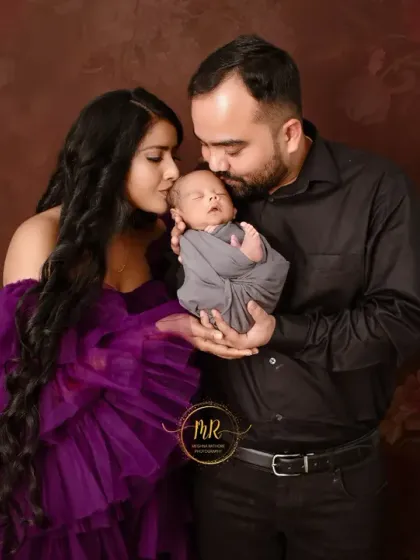 New parents lovingly kiss their newborn baby's head. This photo captures the overwhelming love of the first few days.