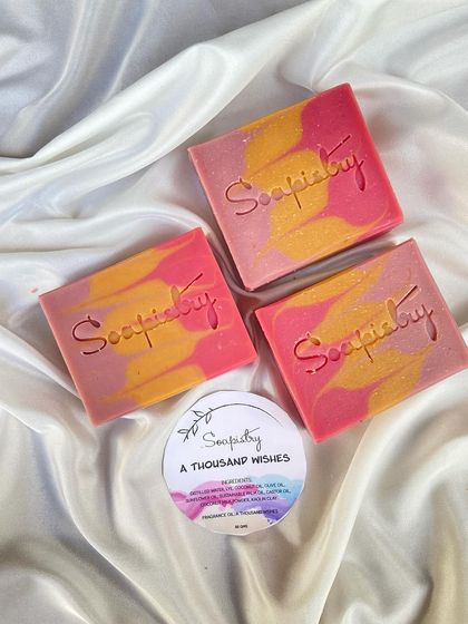The "A Thousand Wishes" soap, with its warm pink and gold tones. Each bar is stamped with the Soapistry logo.