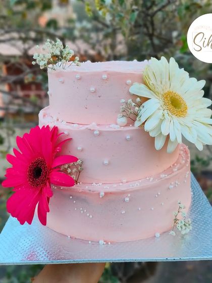 Gerbera daisy glory. This three-tiered pink cake is simply adorned with fresh, vibrant gerbera daisies and baby's breath, proving that sometimes the flowers are all the decoration you need.