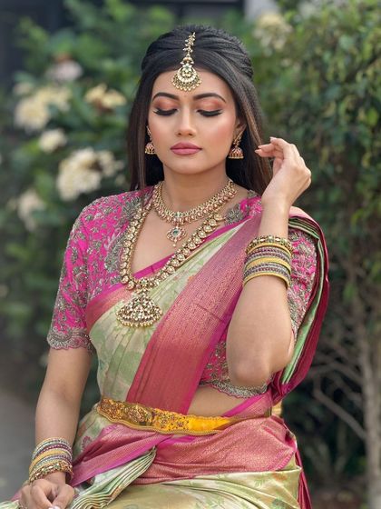 A classic bridal pose, highlighting the soft makeup and the intricate details of her saree and jewelry.
