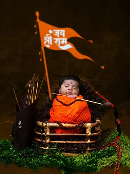 Jai Shri Ram. This powerful newborn shoot features the baby as little Ram, wrapped in saffron cloth, with a bow and arrow and the 'Jai Shri Ram' flag.