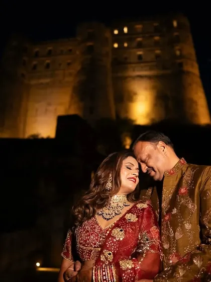 The couple shares a tender moment with the magnificent, lit-up Alila Fort in the background. This shot perfectly combines personal intimacy with the grandeur of a destination celebration.