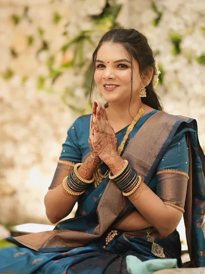 A traditional moment during the engagement ceremony. The bride's teal saree and gold jewellery are paired with a classic makeup look.