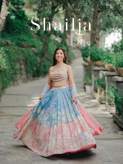 A full-length portrait of the bride, Shailja, in her colorful Mehendi lehenga. Her happy twirl and the lush green background create a vibrant and joyful image.