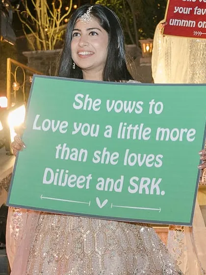 A bridesmaid holds a funny and personal placard for the bride's entry. We love incorporating these inside jokes.