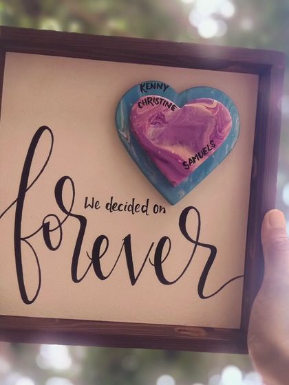 The "forever" anniversary sign, held up to the light. The sunlight creates a beautiful bokeh effect, highlighting the heartfelt nature of this custom gift.