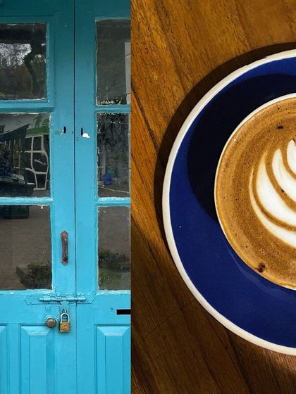 A bright blue door with glass panes, contrasting beautifully with the dark wood of a table holding a cup of coffee.