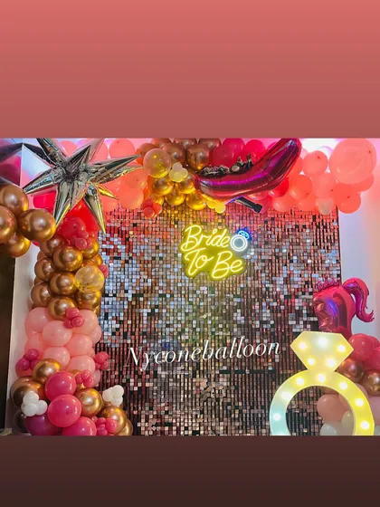 Another view of the 'Bride to Be' decorations, showing how the pink and rose gold balloons complement the sparkling backdrop and light-up ring prop.