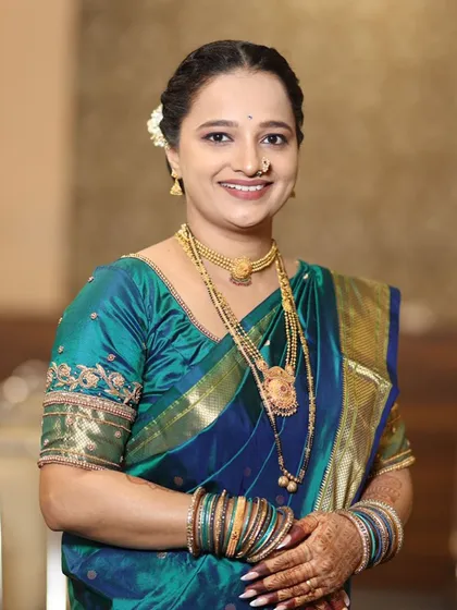 A smiling portrait showing her complete look with traditional gold jewellery.