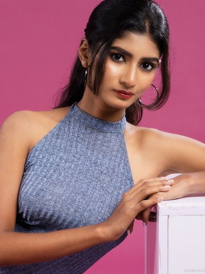 A close-up of the model in the blue halter dress, with a direct and engaging gaze.