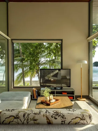 A living area with panoramic views of the ocean and palm trees, showcasing biophilic design. The space is designed to maximize its connection to the natural environment, promoting calm and serenity.