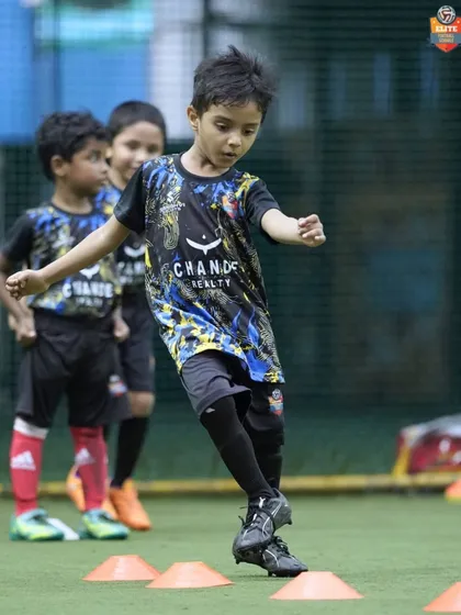 Young players working on their agility by weaving through cones, a classic drill to improve footwork and speed.
