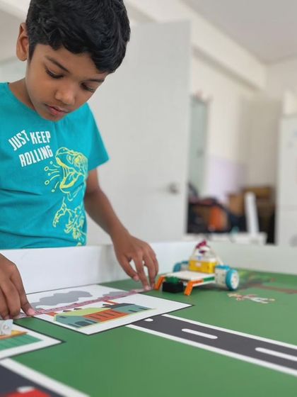 A student carefully places a game piece on the IRO 2024 "Harvest Heroes" mat. This task requires precision and strategic planning, key skills we develop in our training program.