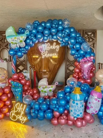 A vibrant baby shower decoration with "Oh Baby" and "Baby Shower" neon signs. The contrasting metallic blue and pink balloons create a bold and energetic atmosphere.