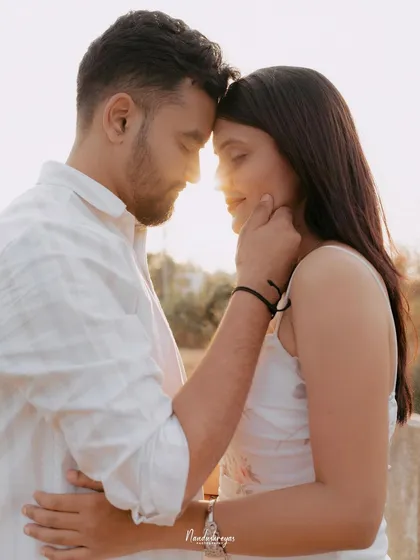 A close-up shot of a couple's embrace, with the golden light of sunset reflecting on their faces by the lake.