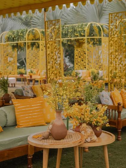 Lounge seating at the 'Bageecha' Haldi, where traditional wooden benches are updated with modern cushions in shades of green and yellow.