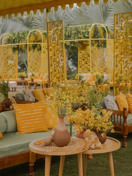 Lounge seating at the 'Bageecha' Haldi, where traditional wooden benches are updated with modern cushions in shades of green and yellow.
