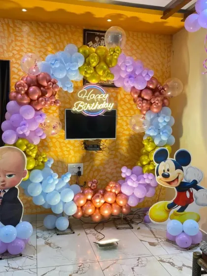 A fun crossover theme with Boss Baby and Mickey Mouse cutouts, set against a multi-colored balloon ring and a neon sign.