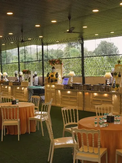 A daytime view of a large-scale event setup, with neatly arranged tables and a long line of buffet counters ready for service. The open, airy space is perfect for lunches and brunches.