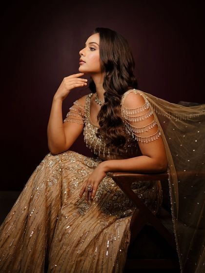 A thoughtful pose showing off the soft curls and the elegant makeup. This look is timeless and sophisticated, perfect for any formal celebration.