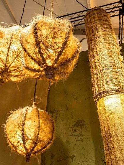 A detail of the lighting within the 'Edge of the Forest' installation. The woven pendants, made from natural fibers, cast a warm, dappled light that enhances the feeling of being in a serene, healing space away from the urban jungle.