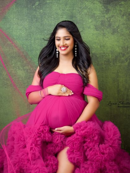 The joy on her face says it all. This beautiful pink ruffled gown brings out the radiant glow of motherhood, creating a portrait that is pure happiness.