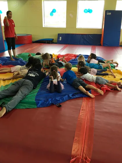 After a fun session, the children relax together on the parachute. This cool-down activity promotes calmness and a sense of shared experience.