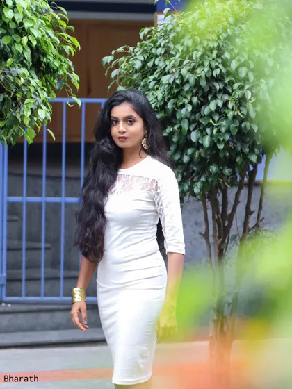 A shot of the model in the white dress, framed by foliage. This creative composition adds depth and interest to the portrait.