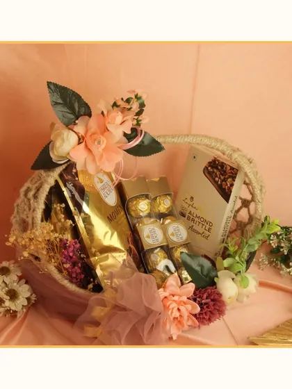 A beautiful peach-themed hamper in a rustic basket. This gift is perfect for a wedding or anniversary, filled with gourmet coffee, Ferrero Rocher, and almond brittle.