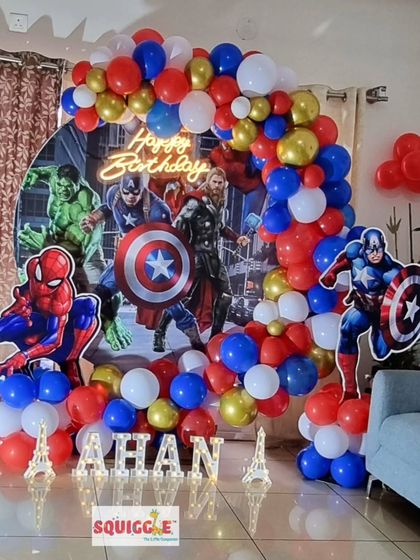 An epic Avengers themed birthday party featuring Captain America, Hulk, Thor, and Spiderman with a circular backdrop and a red, blue, and gold balloon garland.