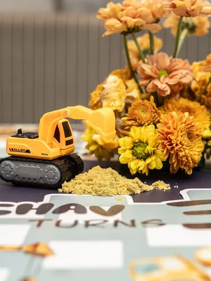 A close-up of the personalized placemat and a toy excavator with edible sand, a detail that delighted the younger guests.
