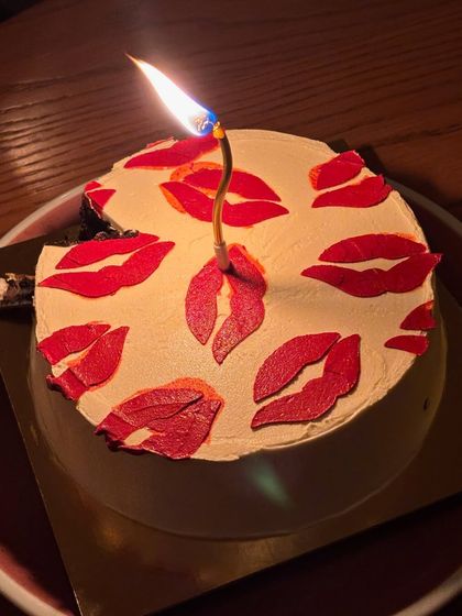 The warm glow of a birthday candle on our kiss cake. It’s ready for a wish to be made.