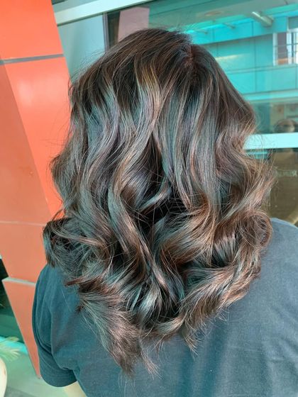 A close-up view of the wavy, highlighted hair. You can see the careful placement of the color, which gives the style a natural and sophisticated feel.
