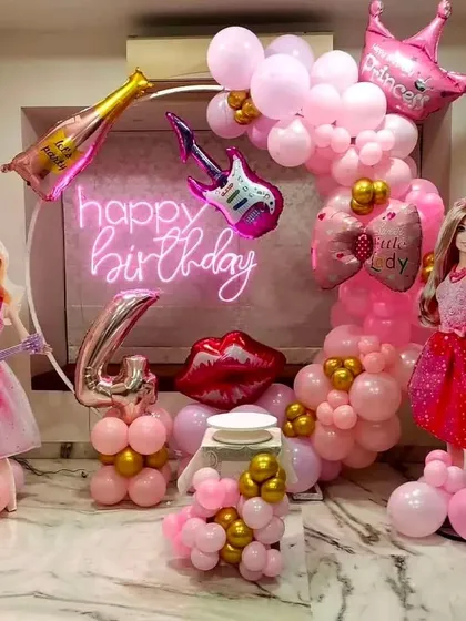 A glamorous Barbie theme for a 4th birthday. The decor is all about pink, with Barbie doll cutouts, a neon sign, and fun-shaped foil balloons like a guitar and lipstick.