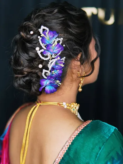 A great hairstyle completes the look. This intricate floral bun is a beautiful example of the hairstyles I create for brides and guests, ensuring every detail is perfect from head to toe. This style works beautifully with both sarees and lehengas.