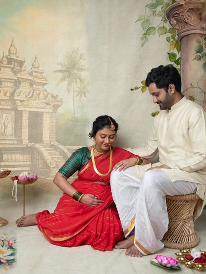 A beautiful scene of a couple sharing a quiet moment. This setup, with traditional elements and a painted temple backdrop, is perfect for a classic Indian maternity portrait.