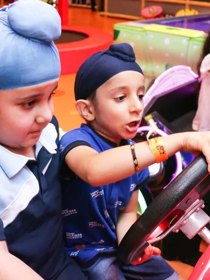 Two young guests learning to share and play together on one of our ride-on car simulators, perfect for imaginative fun.